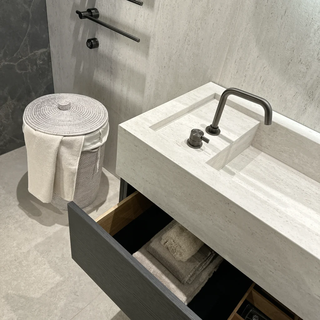 Detail of a custom bathroom vanity with integrated ceramic basin and open TA'OR Box drawer, showcasing expertise in luxury bathroom designs.